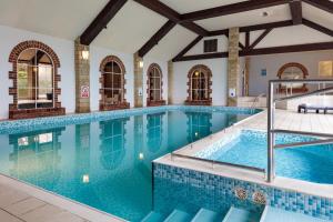 a large swimming pool with blue tiles in a building at Oxford Witney Hotel in Witney