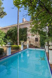 a swimming pool in front of a house with trees at Villa Elvira, exclusive Pool and Gardens in the heart of Sevilla in Seville