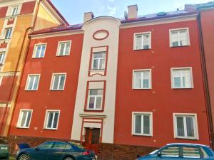 czerwony budynek z samochodami zaparkowanymi przed nim w obiekcie SATYS Apartments w Ostravie