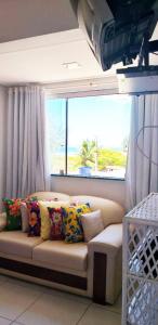 a couch with pillows in a room with a window at Ap aluguel no Guaibim in Guaibim