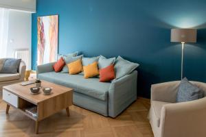 a living room with a blue couch with colorful pillows at DARSISS 2 - Museum Apartment in Athens