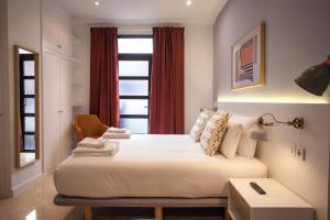 een slaapkamer met een bed met een stoel en een raam bij Gran Central Suites in Madrid