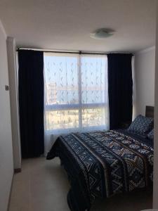 a bedroom with a bed and a large window at Departamento en Serena in Coquimbo +13 photos