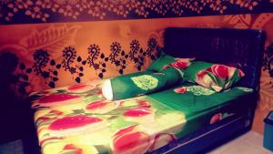 a bedroom with a bed with green sheets and flowers at Nakula's Guest House in Banyuwangi