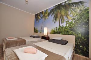 two beds in a room with palm trees on the wall at Apartment Toya in Slatine