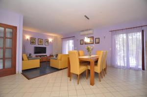 a dining room and living room with a table and yellow chairs at Apartment Toya in Slatine