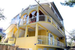 a yellow building with white balconies on it at Apartment Toya in Slatine