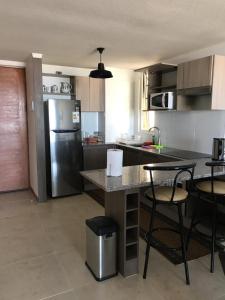 una cocina con nevera de acero inoxidable, mesas y sillas en Departamento en Serena, en Coquimbo