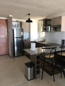a kitchen with a stainless steel refrigerator and tables and chairs at Departamento en Serena in Coquimbo