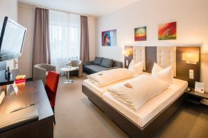 ein Hotelzimmer mit einem großen Bett und einem Schreibtisch in der Unterkunft Hotel Monopol in Gelsenkirchen