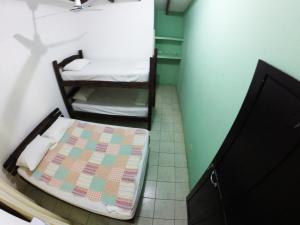 Tsunami Hostel في تاماريندو: غرفة صغيرة مع سرير في غرفة
