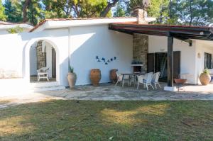 Un patio con una mesa y sillas frente a una casa. en Villa Aurora in Sani with garden and pool, en Sani Beach