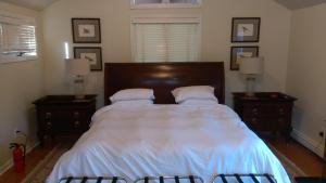 um quarto com uma cama com lençóis brancos e almofadas em Spacious master bedroom and bath em Wellesley