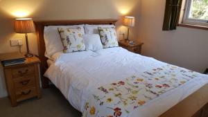 ein Schlafzimmer mit einem großen weißen Bett mit zwei Nachttischen in der Unterkunft The Old Cottage in Arduaine