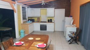 a kitchen with a wooden table and a kitchen with white cabinets at kazAnne in Pointe-Noire