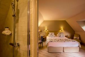 a bedroom with a king sized bed and a shower at Les Manoirs de Tourgéville in Deauville