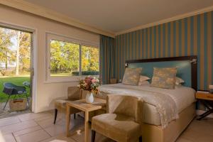 - une chambre avec un lit, une table et des chaises dans l'établissement Les Manoirs de Tourgéville, à Deauville