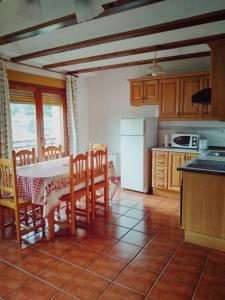 a kitchen with a table and chairs and a refrigerator at Casa Rural Lahuerta Apartamentos GUADALAVIAR in Guadalaviar