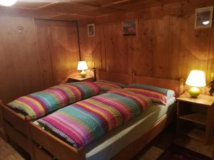 a bed in a wooden room with two lamps at Appartamento Col di Lana Dolomites in Livinallongo del Col di Lana