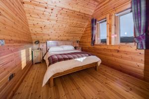 1 dormitorio con 1 cama en una cabaña de madera en Lorien Lodge, en Breakish