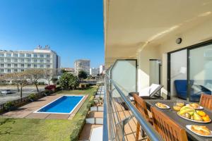 Un balcón con una mesa con comida y una piscina. en MILLENIUM 1 2-2, en Roses