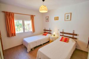 ein Schlafzimmer mit zwei Betten und einem Fenster in der Unterkunft Mabruka - charming, Finca style holiday villa in Benissa in Benissa