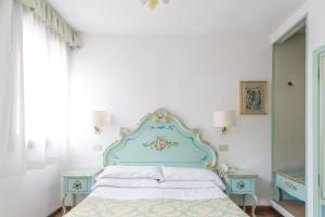 ヴェネツィアにあるホテル セレニッシマのベッドルーム1室(青いヘッドボード付きのベッド1台、テーブル2台付)