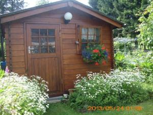 un pequeño cobertizo de madera con una puerta y flores en B & B Le Jardin Bed & Breakfasts, en Ménil