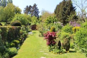 a garden with many bushes and flowers and a bench at B & B Le Jardin Bed & Breakfasts in Ménil