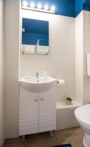 a white bathroom with a sink and a mirror at International Aparthotel in Cluj-Napoca