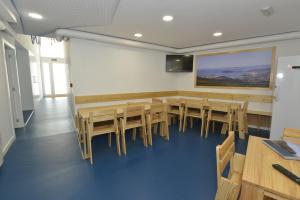 una sala de conferencias con mesas y sillas de madera en Hostel Albergue Baionamar, en Baiona