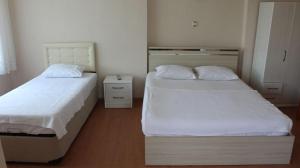 two beds in a small room with white sheets at Bahçeli Konak in Eceabat