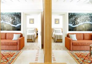 a living room with two orange chairs and two beds at Columbia Beach Resort in Pissouri