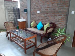 eine Terrasse mit einem Sofa, Stühlen und einem Tisch in der Unterkunft Blue Sands Beach Resort in Pasikuda