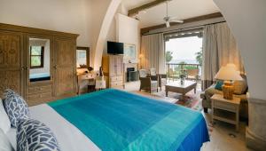 a bedroom with a blue bed and a living room at Columbia Beach Resort in Pissouri