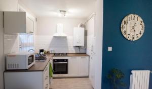 a kitchen with a clock on a blue wall at Appartement hypercentre Tarbes in Tarbes