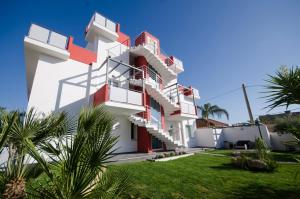 a house with red and white balconies and palm trees at Hotel Rainbow Resort in Marsala