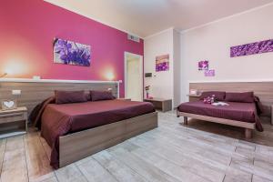 1 dormitorio con 2 camas y pared de color rosa en Suite Room Fiumicino, en Fiumicino