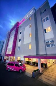 un coche rosa estacionado frente a un edificio en favehotel Kelapa Gading en Yakarta