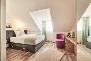 a bedroom with a bed and a purple chair at Hotel Tiffany in Kassel