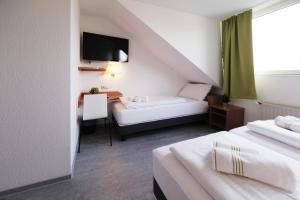una camera d'albergo con due letti, un tavolo e una televisione di bp24 Hotel Aachen ad Aquisgrana