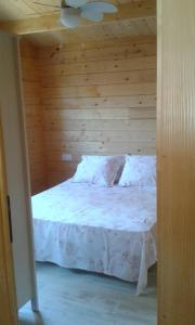 1 dormitorio con cama blanca y pared de madera en Casita de madera junto al mar, en El Puerto de Santa María