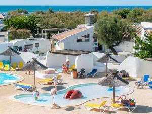 un complexe doté d'une piscine avec des chaises longues et des parasols dans l'établissement Oh! Campings - Le Clos du Rhône, à Saintes-Maries-de-la-Mer