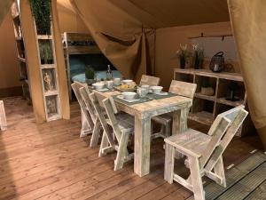 a table and chairs in a room with a tent at Oh! Campings - Le Clos du Rhône in Saintes-Maries-de-la-Mer