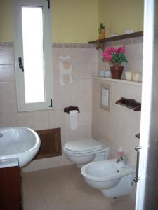 Łazienka z białą toaletą i umywalką w obiekcie Sa Rosa E Su Trapperi w mieście Oschiri