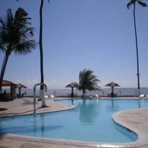 a large swimming pool with palm trees and the ocean at Chalé 01 em Maragogi Brasil Maragogi in Maragogi