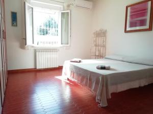 una camera bianca con un letto e una finestra di Villa Maria Apartments a Capoterra