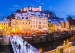 a group of people walking over a bridge over a river with a building at Hanna's suite with free parking in Ljubljana