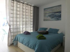 um quarto com uma cama com lençóis azuis e uma janela em BLU em Puerto del Carmen