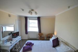 a bedroom with a bed and a desk and a mirror at The Anchorage in Weymouth
